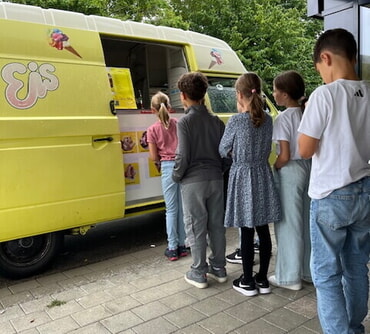 mehrere Kinder stellen sich am Eiswagen an